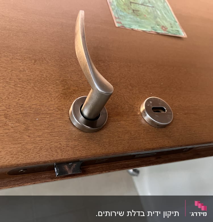 ידית דלת מתכתית על דלת עץ